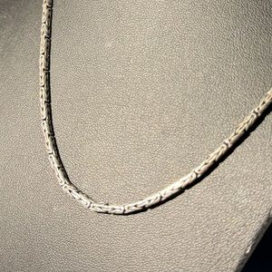Silver necklace with rounded chain and hook clasp closure.